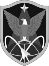 The 1st Space Brigade shoulder sleeve insignia: a shield bearing an eagle with spread wings over a gridded demi-globe, crossed orbital paths and a downward arrowhead, with a star above.